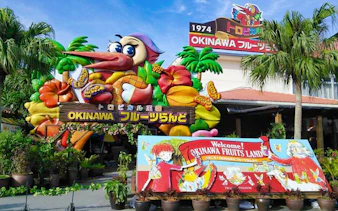 Entrance to Okinawa Fruits Land with colorful tropical fruit decorations and welcome sign.