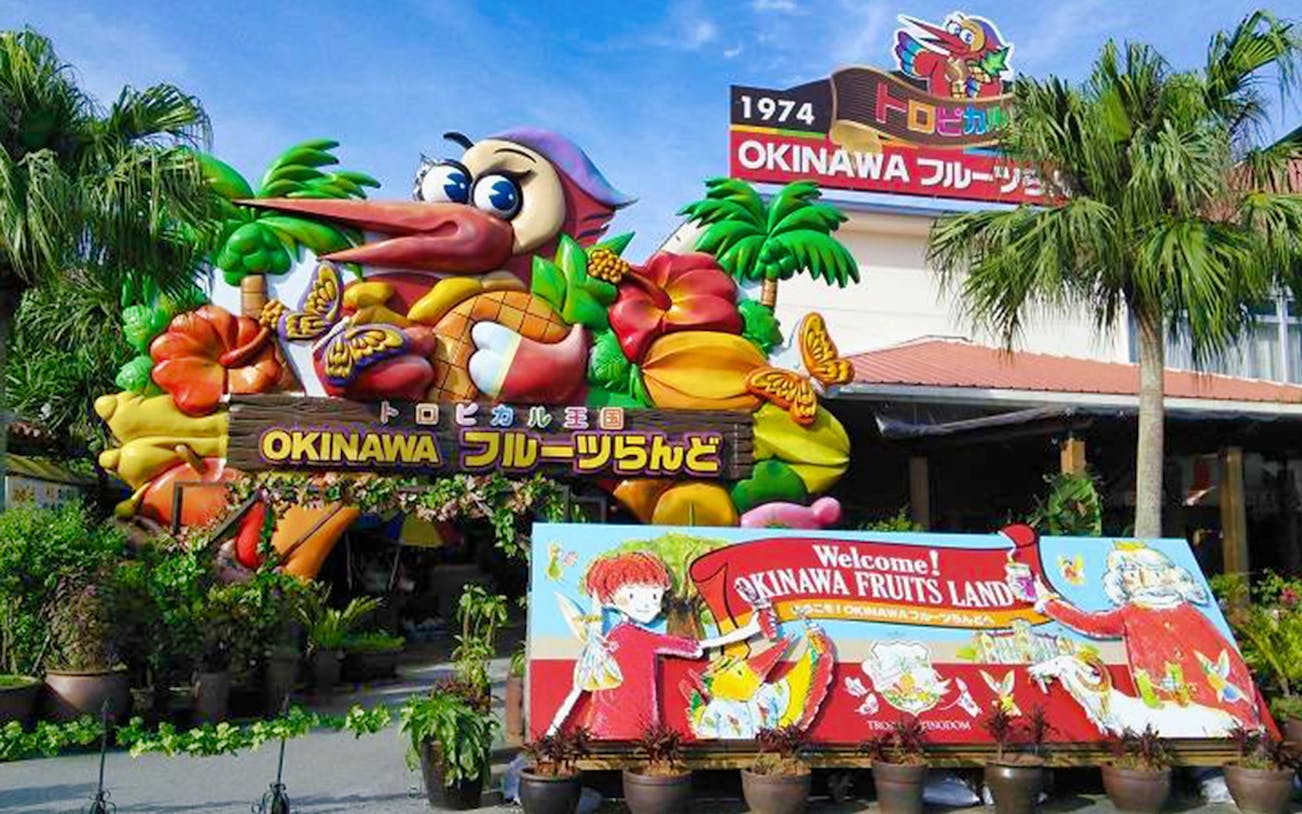 Entrance to Okinawa Fruits Land with colorful tropical fruit decorations and welcome sign.