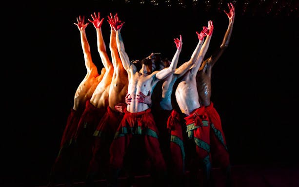 Dancers from Akram Khan Company performing "We are but Shadows" with raised arms.