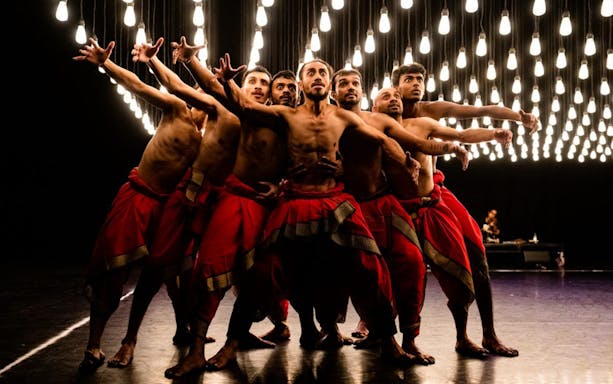Dancers from Akram Khan Company perform under hanging lights in "We are but Shadows.