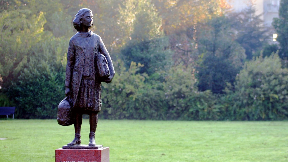 Anne Frank statue in a park setting, Amsterdam.