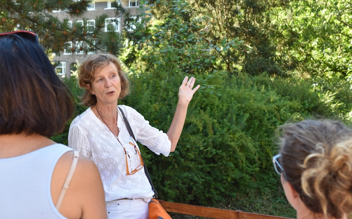 Tour guide leading Anne Frank Walking Tour in Amsterdam garden setting.