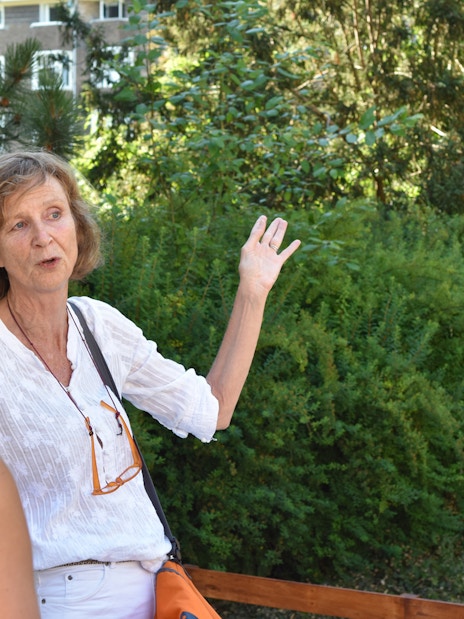 Tour guide leading Anne Frank Walking Tour in Amsterdam garden setting.