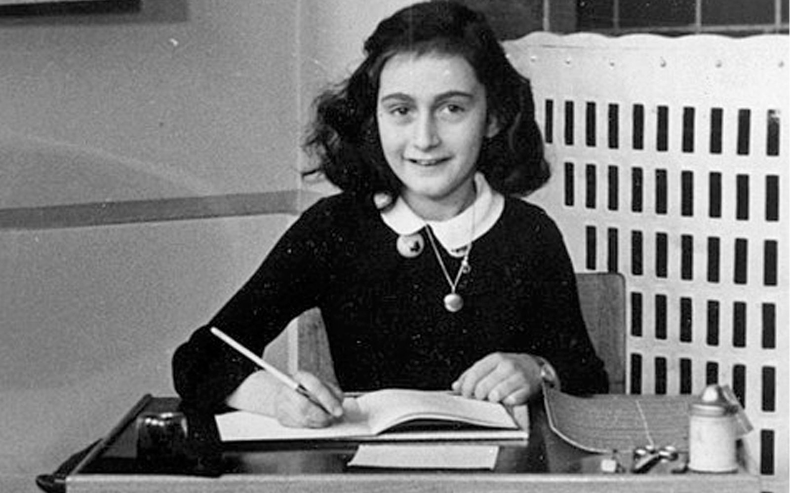 Young girl writing at a desk, archival image related to Anne Frank.