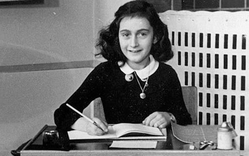 Young girl writing at a desk, archival image related to Anne Frank.