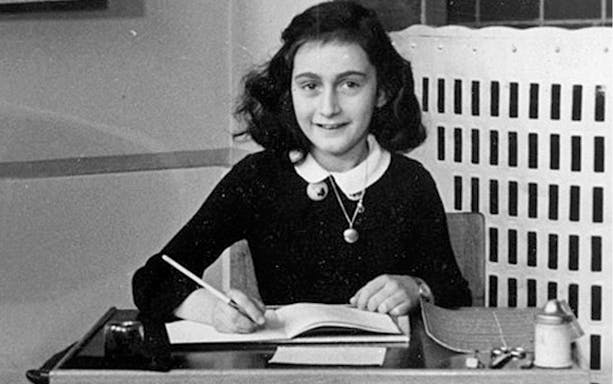 Young girl writing at a desk, archival image related to Anne Frank.