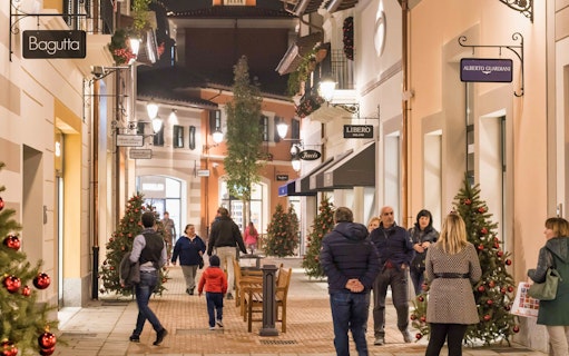 Shoppers walking through decorated street at Serravalle Designer Outlet near Milan.