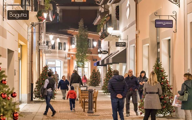 Shoppers walking through decorated street at Serravalle Designer Outlet near Milan.