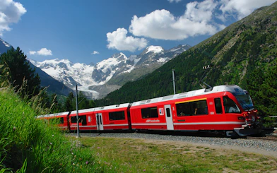 Red Bernina Express train traveling through Swiss Alps near St. Moritz.