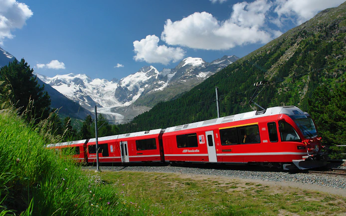 Red Bernina Express train traveling through Swiss Alps near St. Moritz.