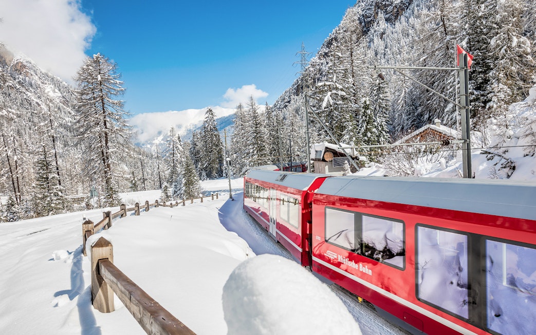 Bernina Express train traveling through snowy Alps on a full-day tour from Milan to St. Moritz.