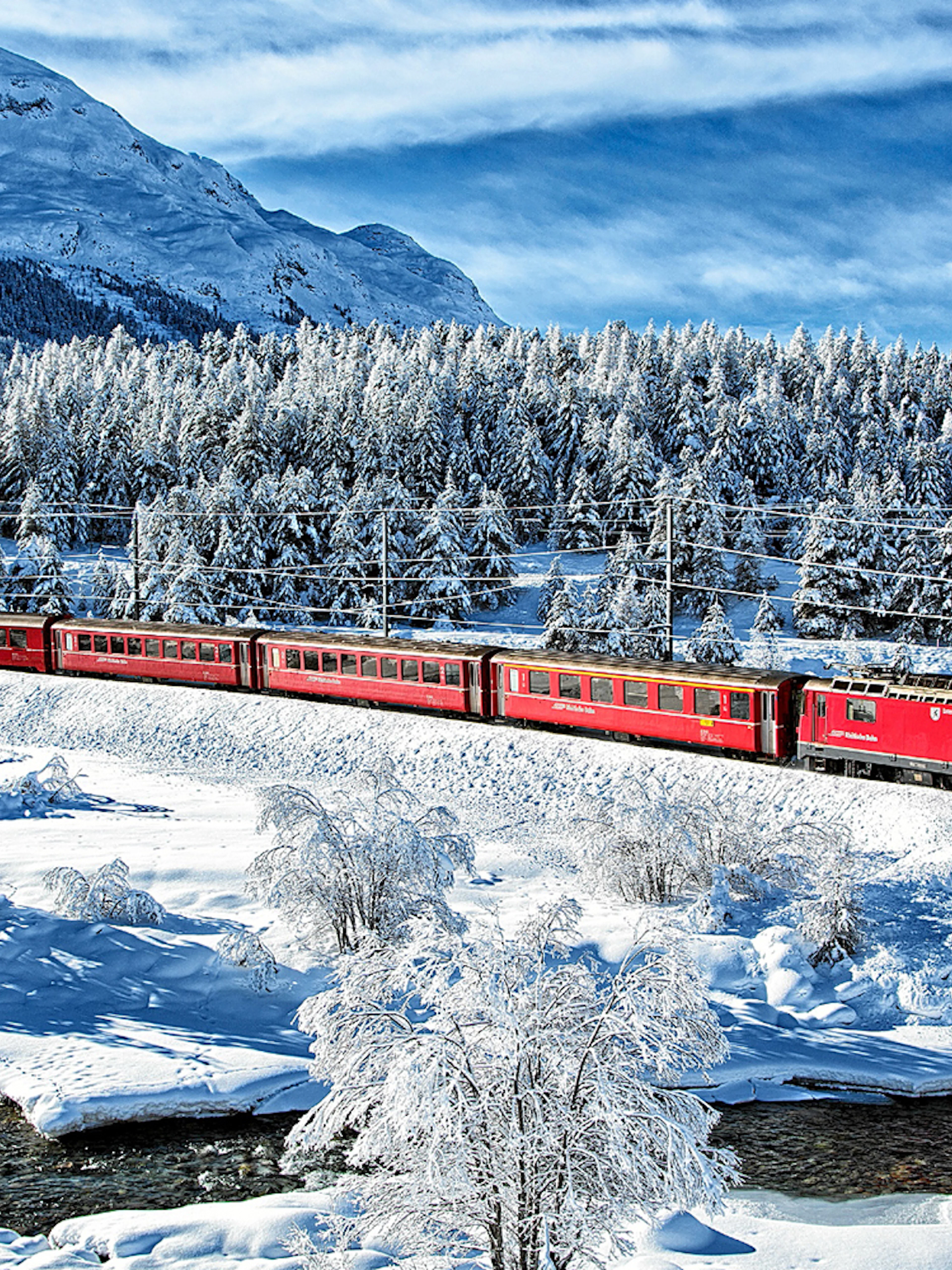 Bernina Express traveling through snowy landscape near St Moritz on a full day tour.