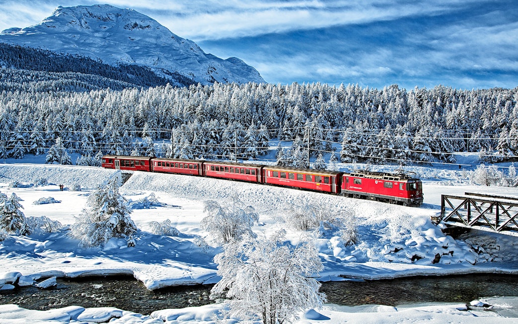 Bernina Express traveling through snowy landscape near St Moritz on a full day tour.