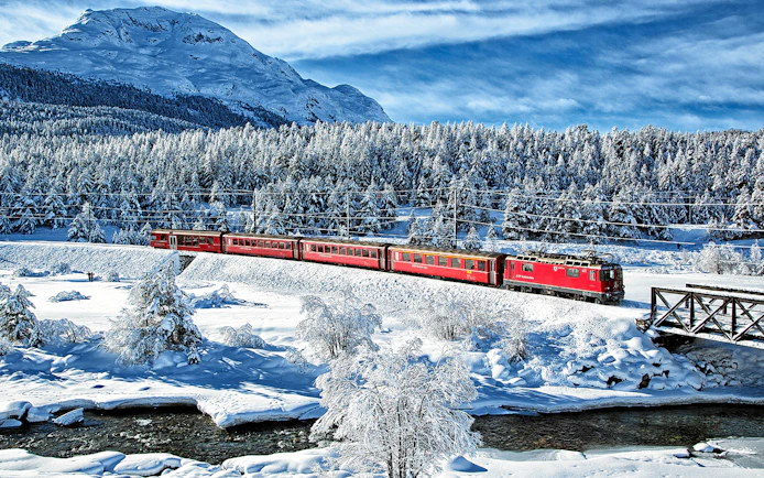 Bernina Express traveling through snowy landscape near St Moritz on a full day tour.