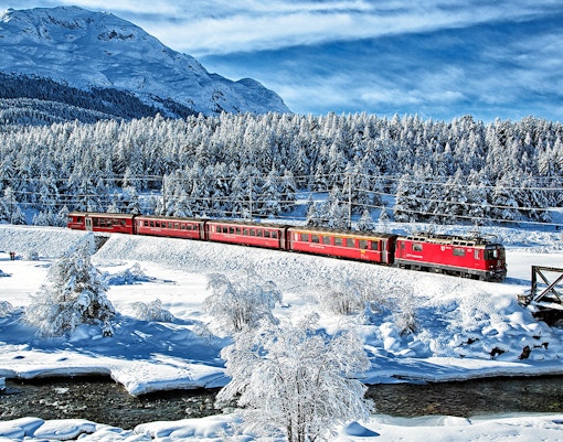 Bernina Express train traveling through snowy Alps on St Moritz full day tour.
