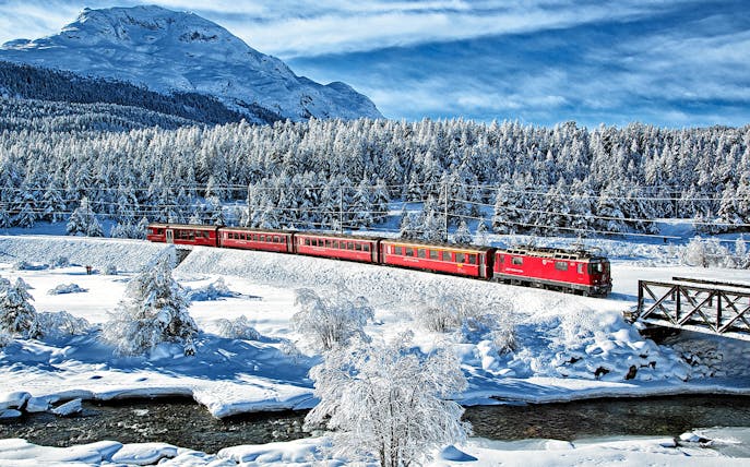 Bernina Express traveling through snowy landscape near St Moritz on a full day tour.