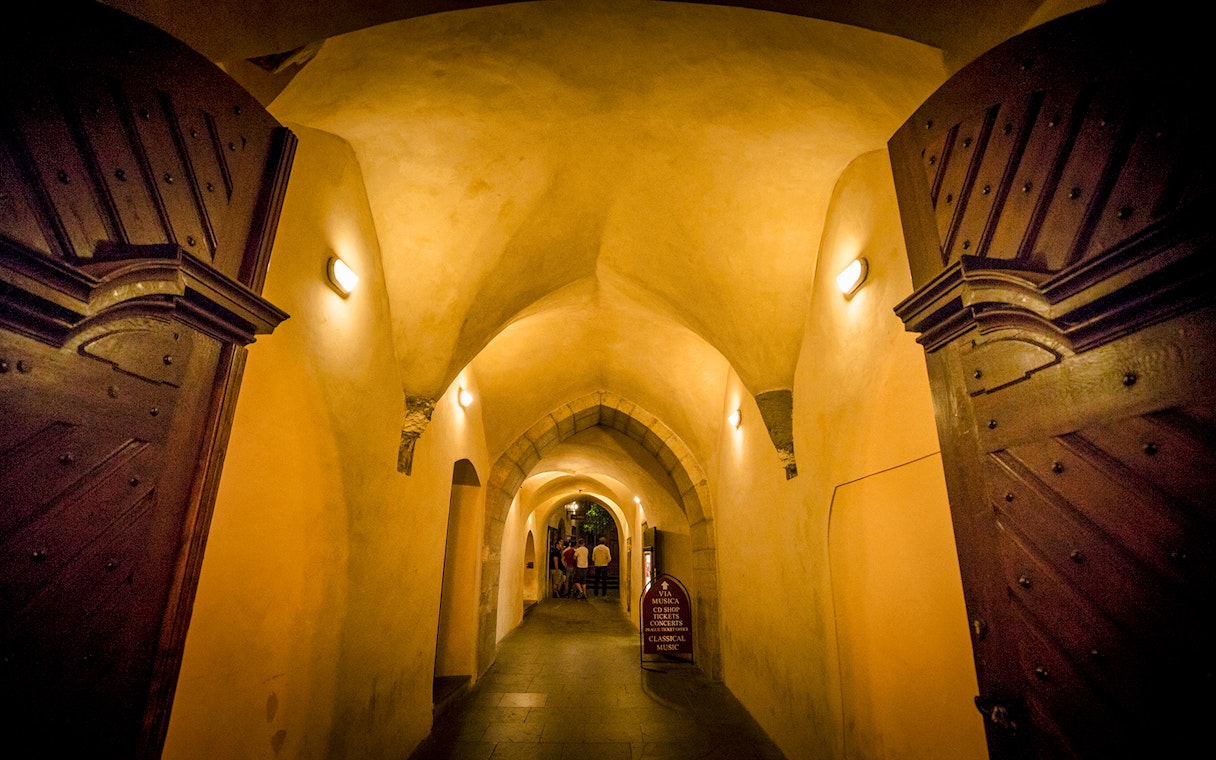 Dimly lit arched hallway in Prague's Old Town, part of the evening ghost tour.