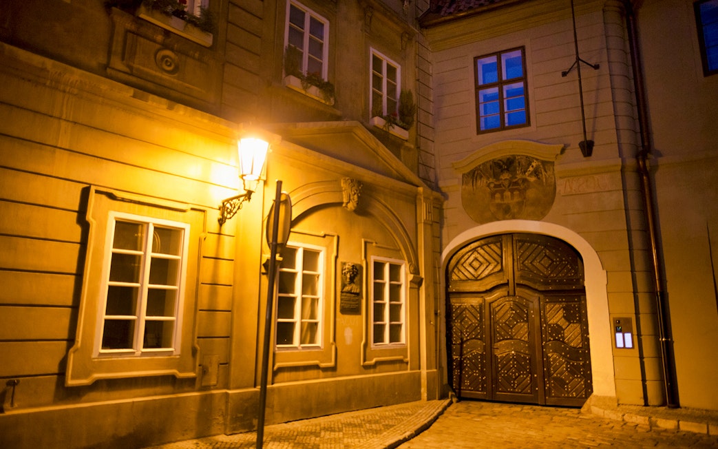Historic Prague street at night with illuminated old town architecture.