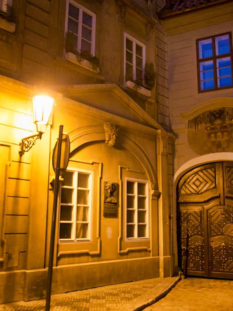 Historic Prague street at night with illuminated old town architecture.