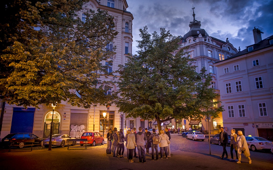 Group gathered under streetlights in Prague's Old Town for an evening ghost tour.
