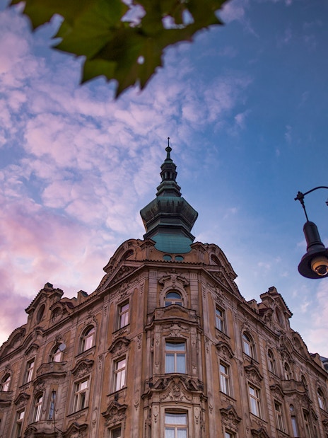 Historic building and street lamp at sunset in Prague's Old Town.