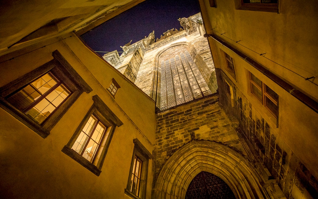 Gothic architecture in Prague's Old Town at night, viewed from a narrow alley.