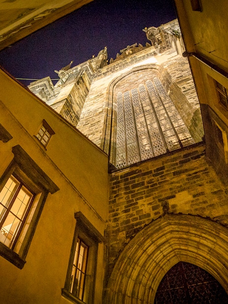 Gothic architecture in Prague's Old Town at night, viewed from a narrow alley.