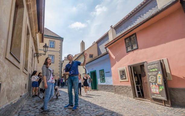 Tourists exploring a cobblestone street in Prague with colorful historic buildings.