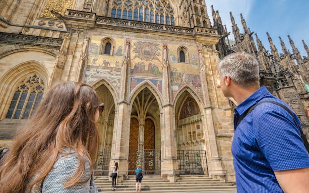 Tourists admiring the facade of St. Vitus Cathedral in Prague during a walking tour.