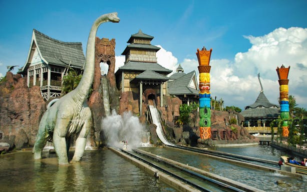 Leofoo Village Theme Park water ride with dinosaur statue and colorful totem poles.