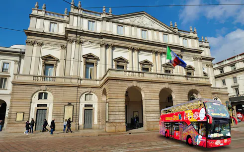 La Scala opera house with a red hop-on-hop-off tour bus in Milan, Italy.