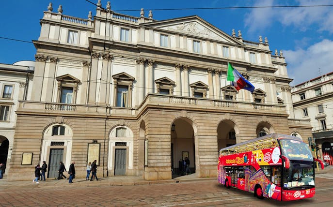 La Scala opera house with a red hop-on-hop-off tour bus in Milan, Italy.