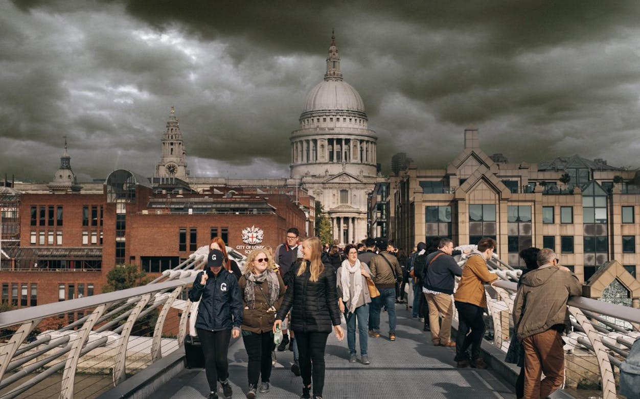 Visitors walking on Millennium Bridge with St. Paul's Cathedral in the background, London.