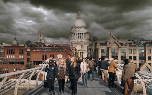 Visitors walking on Millennium Bridge with St. Paul's Cathedral in the background, London.