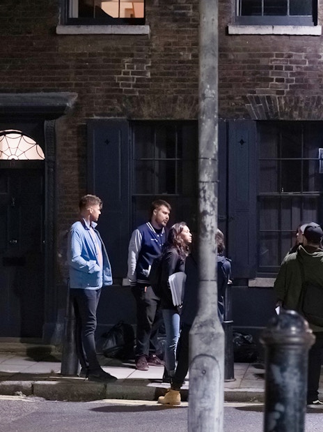 Group of people on a Jack the Ripper tour standing outside historic London building at night.