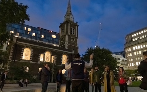 Tour guide leading a group near a historic church on the Jack the Ripper Tour in London.
