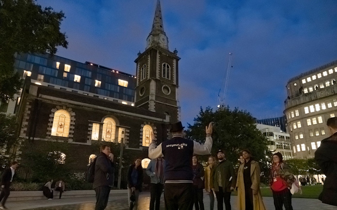 Tour guide leading a group near a historic church on the Jack the Ripper Tour in London.