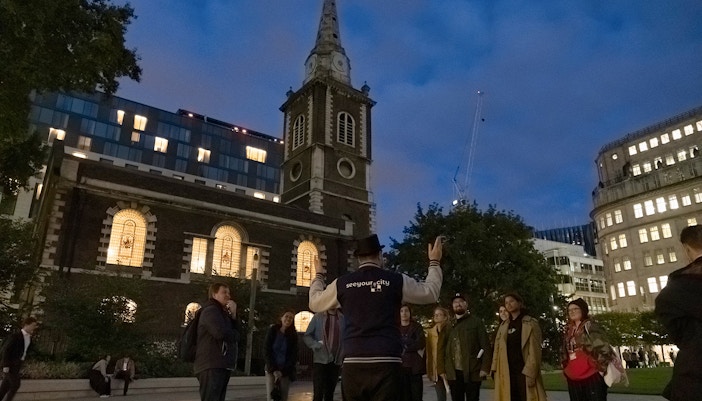 Tour guide leading a group near a historic church on the Jack the Ripper Tour in London.