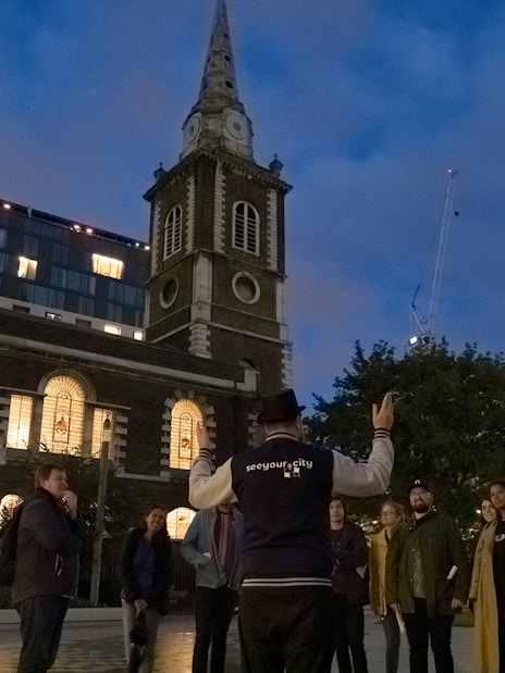 Tour guide leading a group near a historic church on the Jack the Ripper Tour in London.