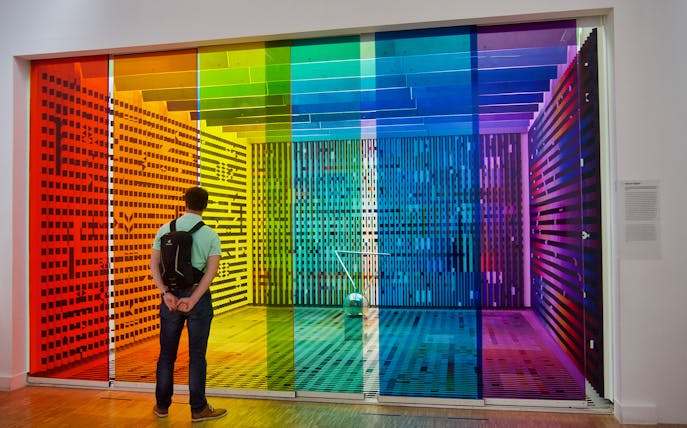 Visitor observing colorful art installation at Centre Pompidou, Paris.