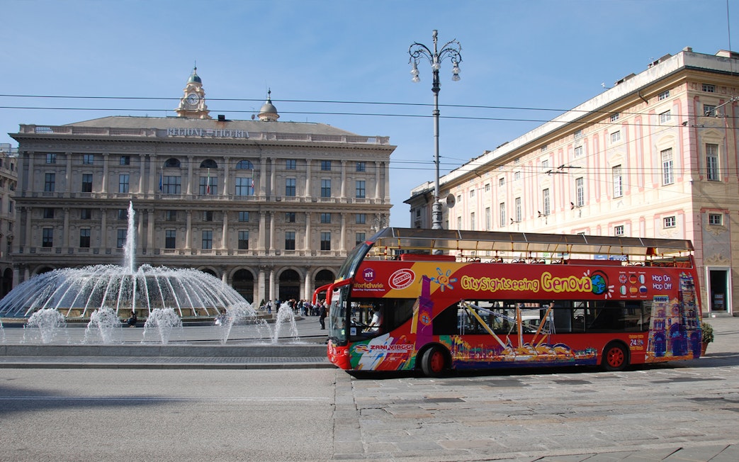 Hop-on-hop-off bus in front of Piazza De Ferrari fountain, Genoa.