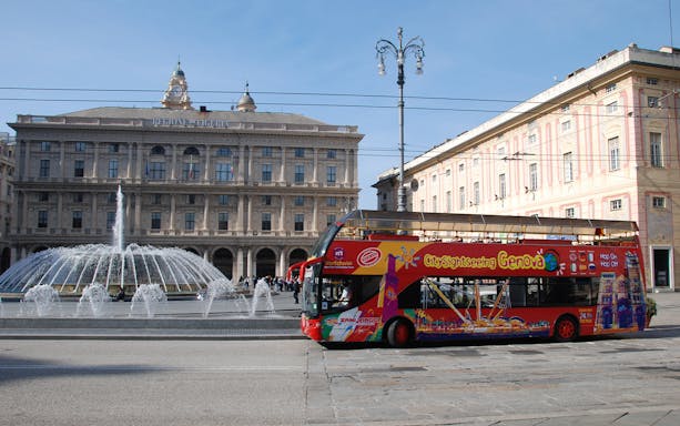 Hop-on-hop-off bus in front of Piazza De Ferrari fountain, Genoa.