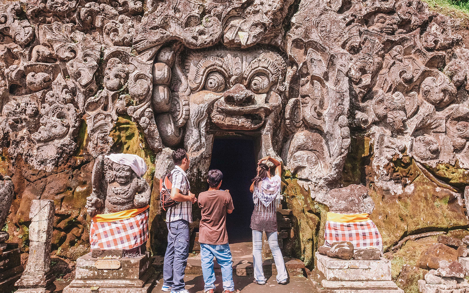 Goa Gajah entrance with intricate stone carvings, Ubud, Bali, visited by tourists.