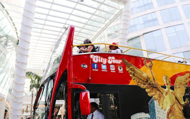 Open-top tour bus in Mexico City with passengers enjoying the view.