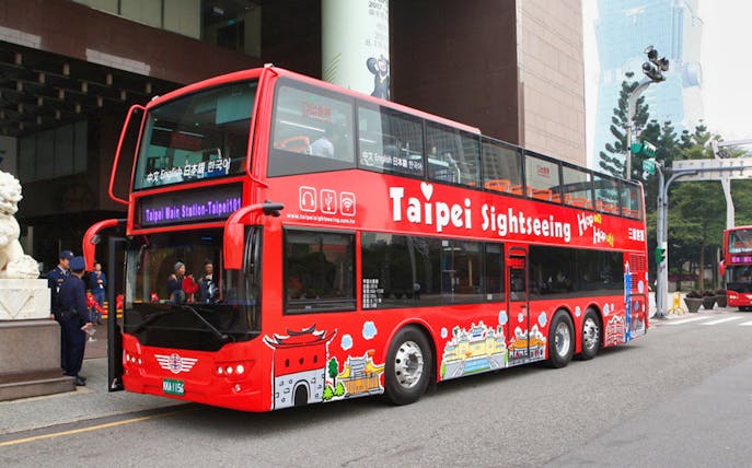 Red double-decker Taipei sightseeing bus at a city stop, ready for hop-on hop-off tour.