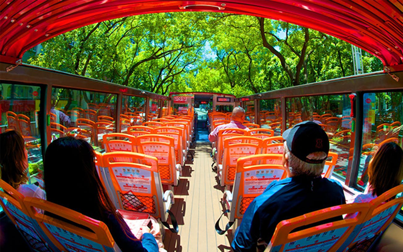 Passengers on Taipei Hop-On Hop-Off bus with open roof and city views.