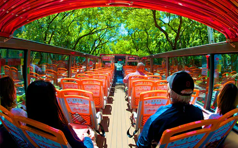 Passengers on Taipei Hop-On Hop-Off bus with open roof and city views.