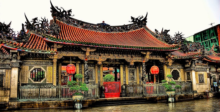 Lungshan Temple entrance in Taipei, featuring ornate carvings and red lanterns.