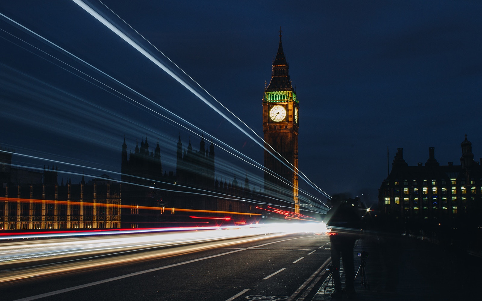 Big Ben illuminated at night with light trails from passing traffic, London.