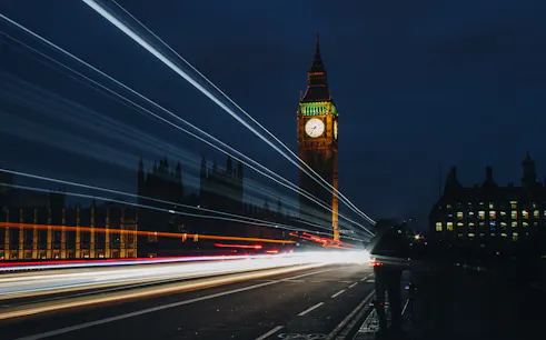 Big Ben illuminated at night with light trails from passing traffic, London.